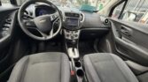 Interior of a Chevrolet car shown from the back seats: driver and passenger seats, steering wheel, and center console with touchscreen.