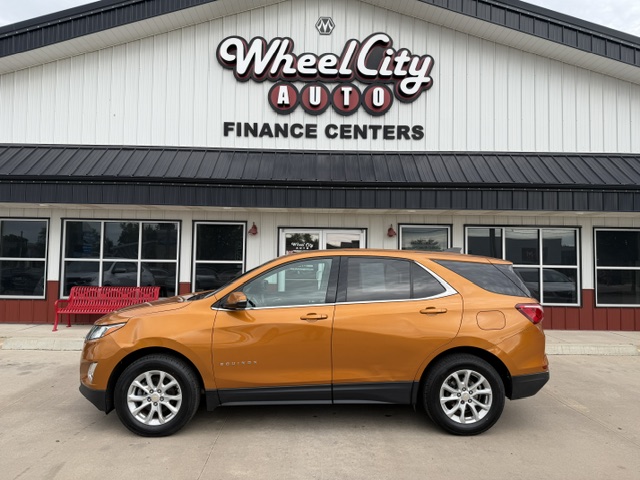 Orange SUV parked in front of Wheel City Auto Finance Centers storefront.
