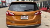 Orange Chevrolet Equinox seen from the rear in a dealership lot, with a Wheel City Auto Finance Centers license plate frame.
