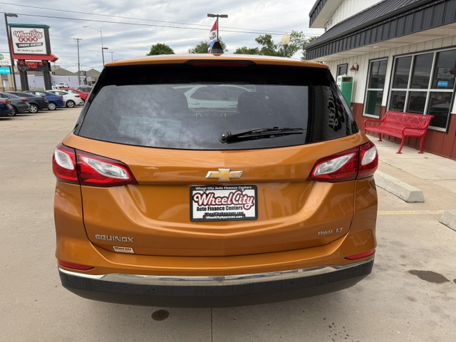 Orange Chevrolet Equinox seen from the rear in a dealership lot, with a Wheel City Auto Finance Centers license plate frame.