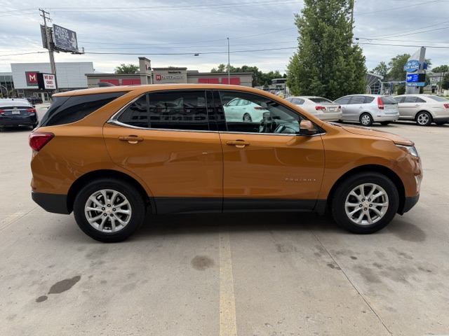Orange-brown Chevrolet Equinox SUV parked in a dealership lot, side view with tinted windows and silver wheels.