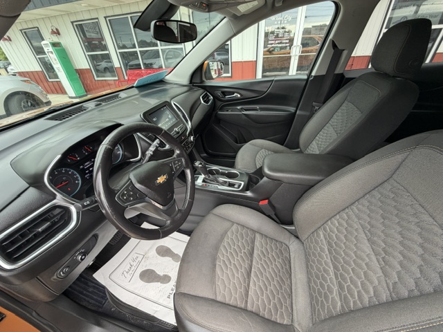 Interior view of a Chevrolet car showing the steering wheel, dashboard, and gray cloth front seats