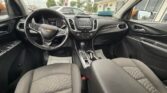 Front interior of a Chevrolet vehicle, showing steering wheel, center touchscreen, gear shifter, and two front seats.