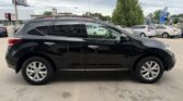 Black mid-size SUV in a parking lot, shown from the side with other cars and a tree in the background.