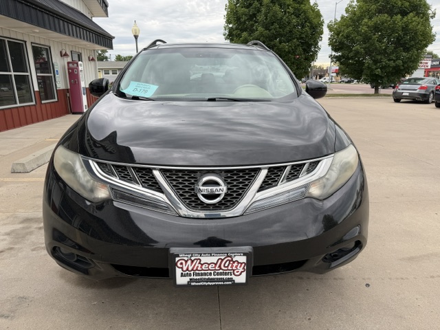 Front view of a black Nissan SUV in a dealership lot, showing the Nissan emblem on the grille and a Wheel City Auto Finance Centers license plate frame.