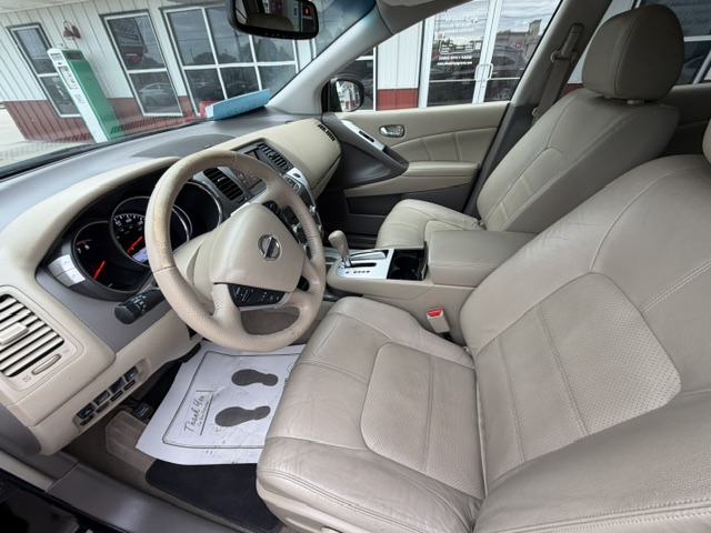Front interior of a beige leather SUV, showing the steering wheel, dashboard, and center console from the driver's seat view.