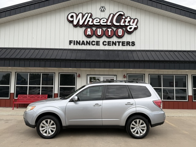 Silver SUV parked in front of Wheel City Auto Finance Centers dealership sign on a white building facade.