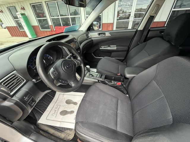 Interior of a dark fabric-seat car, with the steering wheel and center console visible from the driver’s side.