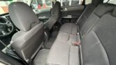 Interior of a black fabric SUV showing the front two seats and a three-seat rear bench with headrests and rubber floor mats.