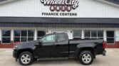 Black pickup truck parked in front of Wheel City Auto Finance Centers storefront sign.