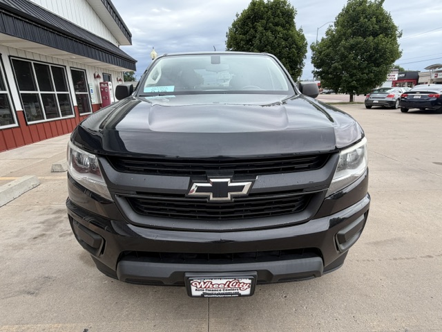 Front view of a black Chevrolet pickup truck parked outside a dealership, showing the Chevy emblem on the grille.
