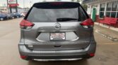 Rear view of a gray Nissan Rogue SUV in a dealership lot, showing taillights, rear wiper, and a Wet City Auto Finance Center license plate frame.