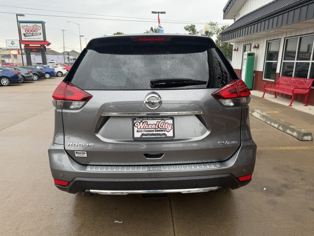Rear view of a gray Nissan Rogue SUV in a dealership lot, showing taillights, rear wiper, and a Wet City Auto Finance Center license plate frame.