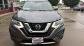 Front view of a gray Nissan SUV on a wet dealership lot, showing the V‑motion grille and headlights, with a Wheel City Auto Finance Centers license plate frame.