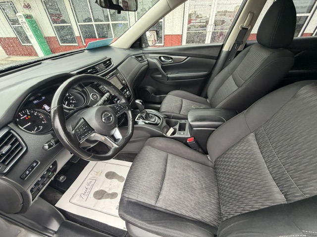 Interior view of a modern car: driver and front passenger seats, steering wheel, and center console with gear shifter.