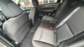 Rear passenger area of a car with black fabric seats, three headrests, and visible seat belts