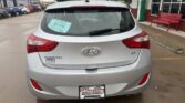 Rear view of a silver Hyundai Elantra GT parked at a dealership; blue sale sticker on the rear window and Wheel City Auto Finance Centers license plate frame visible.