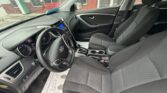 Inside a gray Hyundai sedan: front seats with black fabric, steering wheel with Hyundai logo, and center console with gear shifter visible