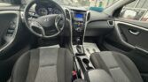 Front interior of a Hyundai sedan with steering wheel, illuminated gauges, center console and automatic gear shifter, front seats visible.