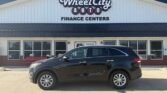 Black SUV parked in front of Wheel City Auto Finance Centers building with large sign above entry.