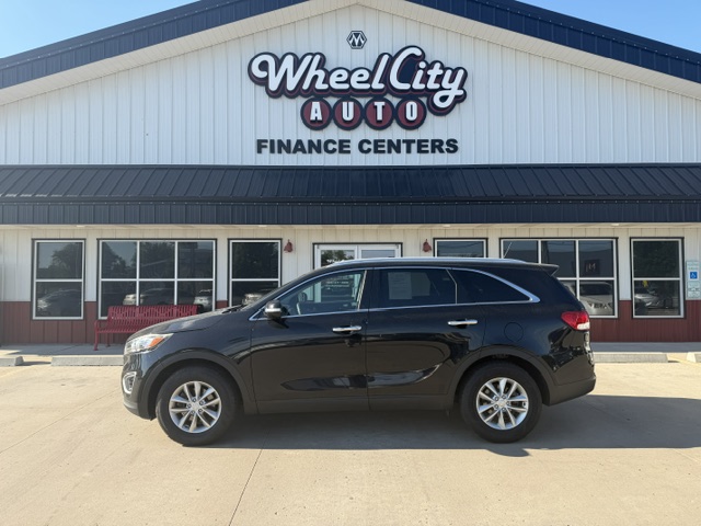 Black SUV parked in front of Wheel City Auto Finance Centers building with large sign above entry.