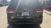 Rear view of a black Kia Sorento SUV in a dealership lot, with a Wheel City Auto Finance Centers license plate frame and showroom building in the background.