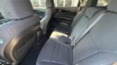 Interior of a car showing gray fabric back seats with headrests and seat belts visible from the rear passenger area