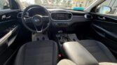 Front interior of a Kia, showing black cloth seats, steering wheel, and center console with touchscreen.