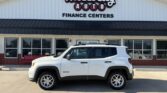 White SUV parked in front of Wheel City Auto Finance Centers dealership with its sign above the storefront.