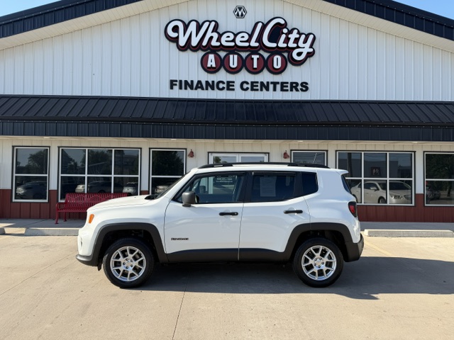 White SUV parked in front of Wheel City Auto Finance Centers dealership with its sign above the storefront.