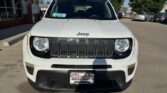 Front view of a white Jeep SUV with seven-slot grille parked in a dealership lot; price tag visible on the windshield.