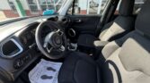Front cabin view of a black SUV with steering wheel (Jeep logo), dashboard, gear shifter, and fabric driver/passenger seats in a dealership setting.