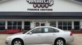 Silver sedan parked in front of Wheel City Auto Finance Centers storefront.