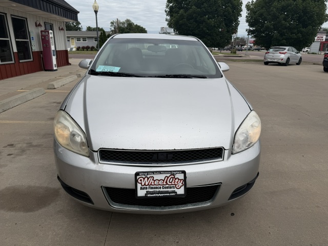 Front view of a silver sedan in a parking lot, dealership plate reads Wheel City Auto Finance Centers.