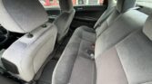 Interior of a gray fabric sedan showing the rear bench seat with three seat belts and the front seats, door panels, and floor mats visible.