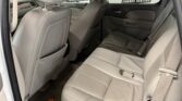 Rear interior of a light-colored SUV with beige leather seats, showing the front seats and back bench, beige carpet, and door panels.
