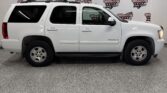 White Chevrolet Tahoe SUV parked indoors in front of a Wheel City Auto banner backdrop.