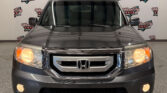 Front view of a gray Honda SUV at a car dealership, headlights on, with Wheel City Auto Finance Centers backdrop and front license plate area visible