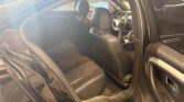 Interior of a black SUV with black leather seats; front seats and steering wheel visible through an open rear door in daylight.
