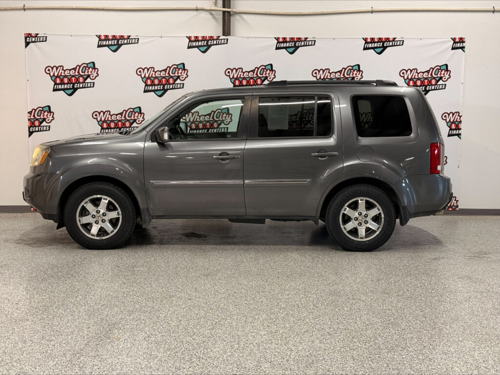 Side view of a gray full-size SUV indoors, in front of a Wheel City Auto Finance Centers backdrop.
