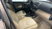 Interior of a beige sedan: driver and front passenger seats, steering wheel, center console, and dashboard.