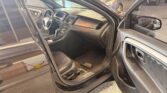 Interior of a dark SUV with the driver's door open, showing steering wheel, dashboard, center console, and front seats in a showroom.