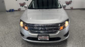 Front view of a silver Ford SUV in a showroom, with a Wheel City Auto Finance Centers banner in the background and license plate visible at the bottom left corner of the image.