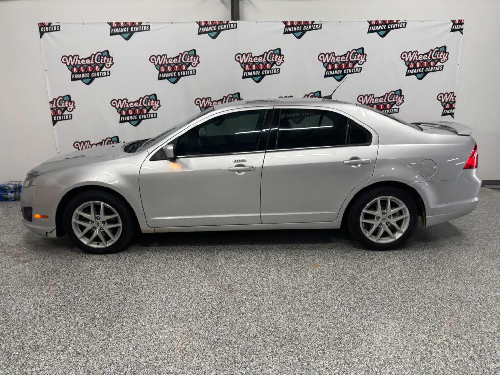 Silver sedan parked in a showroom with a Wheel City Auto Finance Centers banner backdrop