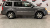 Side view of a gray Honda SUV with roof rails parked indoors in front of a Wheel City Auto Finance Centers backdrop.