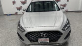 Front view of a silver Hyundai SUV in a showroom with a Wheel City Auto Finance Centers backdrop behind it.