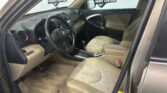 Interior of a beige Toyota SUV: steering wheel, dashboard, center console, driver and front passenger seats, with 'RAV4' floor mat visible