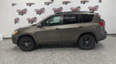 Taupe SUV parked indoors in a showroom with a repeated Wheel City Auto Finance Centers banner in the background.