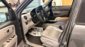 Interior of a gray SUV with the driver’s door open, showing steering wheel, dash, center console, and beige front seats.