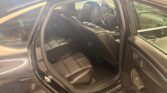 Open rear door reveals black leather car interior with visible driver seat and front passenger seat; steering wheel bears Chevrolet logo in a parked vehicle.